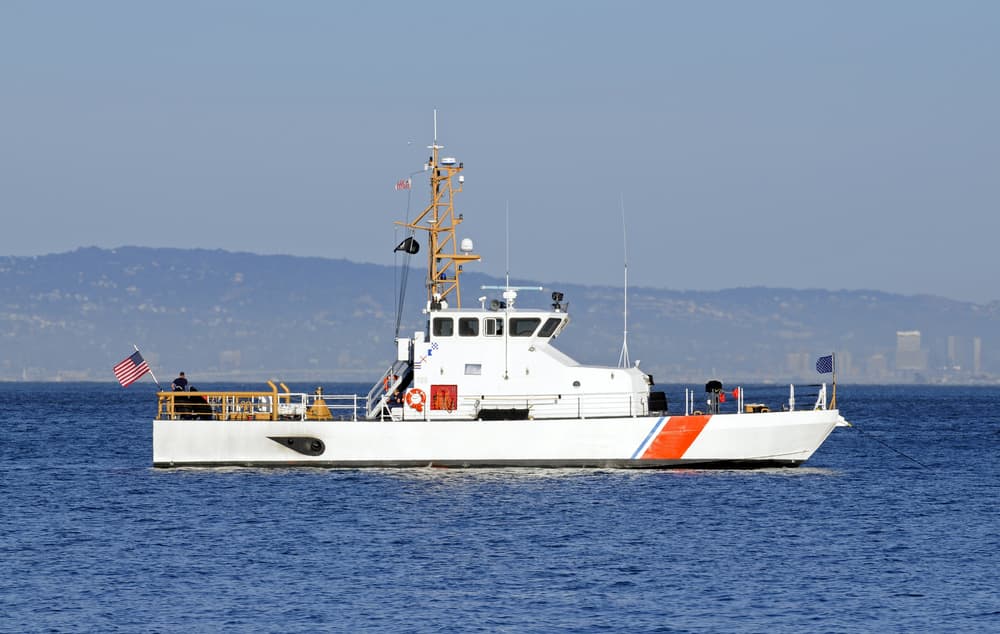A US Coast Guard patrol ship is anchored at sunset while on patrol.