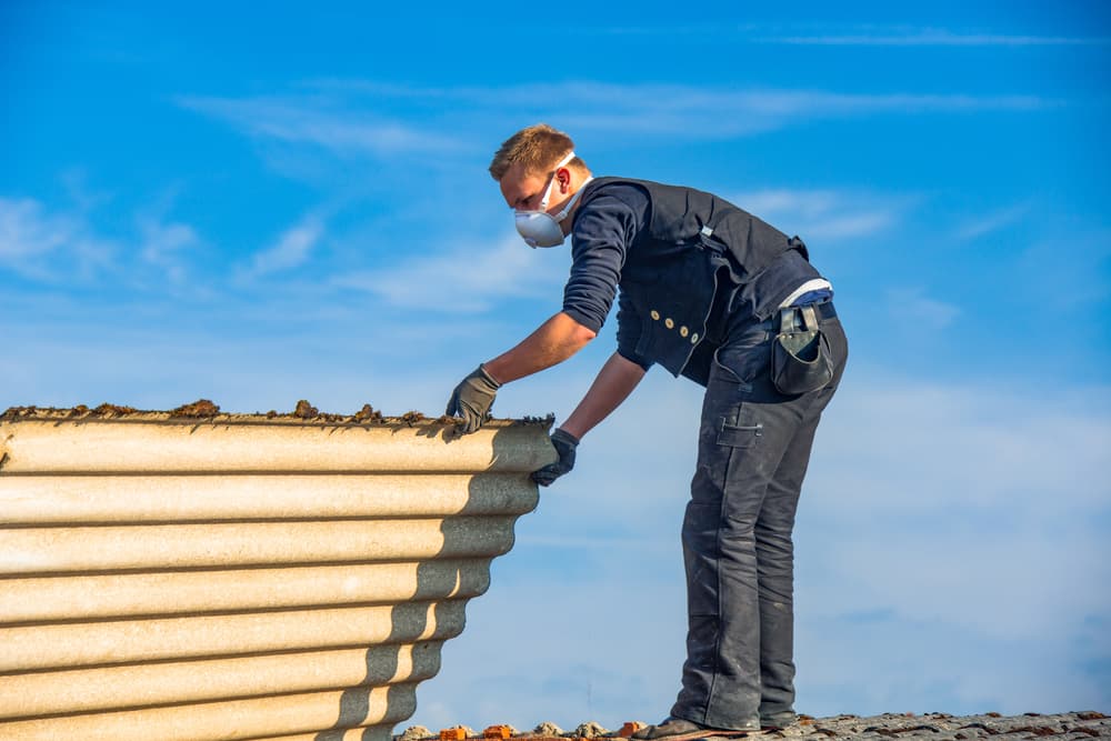 A roofer renovating a flat roof containing asbestos