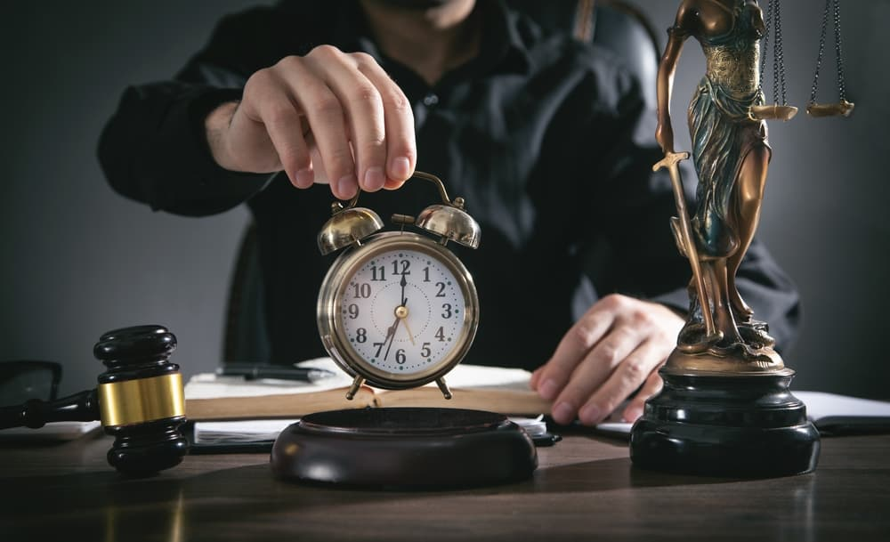 Male judge holding alarm clock at courtroom.