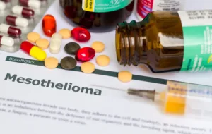 Medical diagnosis of Mesothelioma displayed on white paper with medication, injection, syringe, and pills