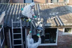 Men in protective suits removing asbestos cement roofing