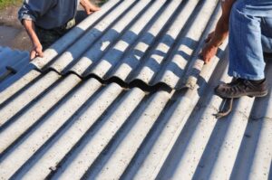 Asbestos roofing construction: Roofers installing asbestos roof sheets. 