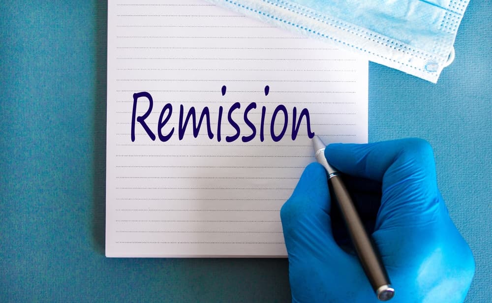 A doctor writing Remission on a pad