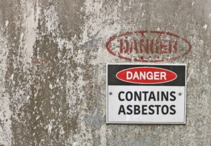 A red, black, and white warning sign that reads "Danger: Contains Asbestos." 