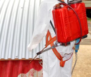 A worker wearing a full protective suit, including a respirator and gloves, during the remediation of asbestos. 