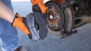 Mechanic's hands showing old, worn out brake pads