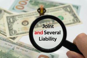 Joint and Several Liability.Magnifying glass showing the words. Background of banknotes and coins.