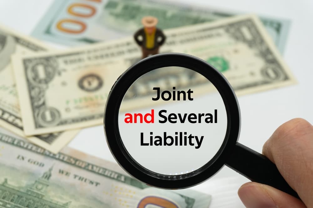 Joint and Several Liability.Magnifying glass showing the words. Background of banknotes and coins.